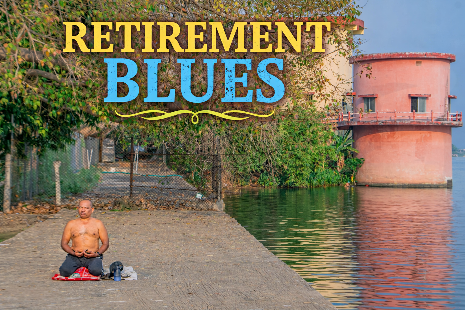 A man sits cross-legged in meditation on a concrete platform beside a calm water body, with trees and a cylindrical building reflected in the water.
