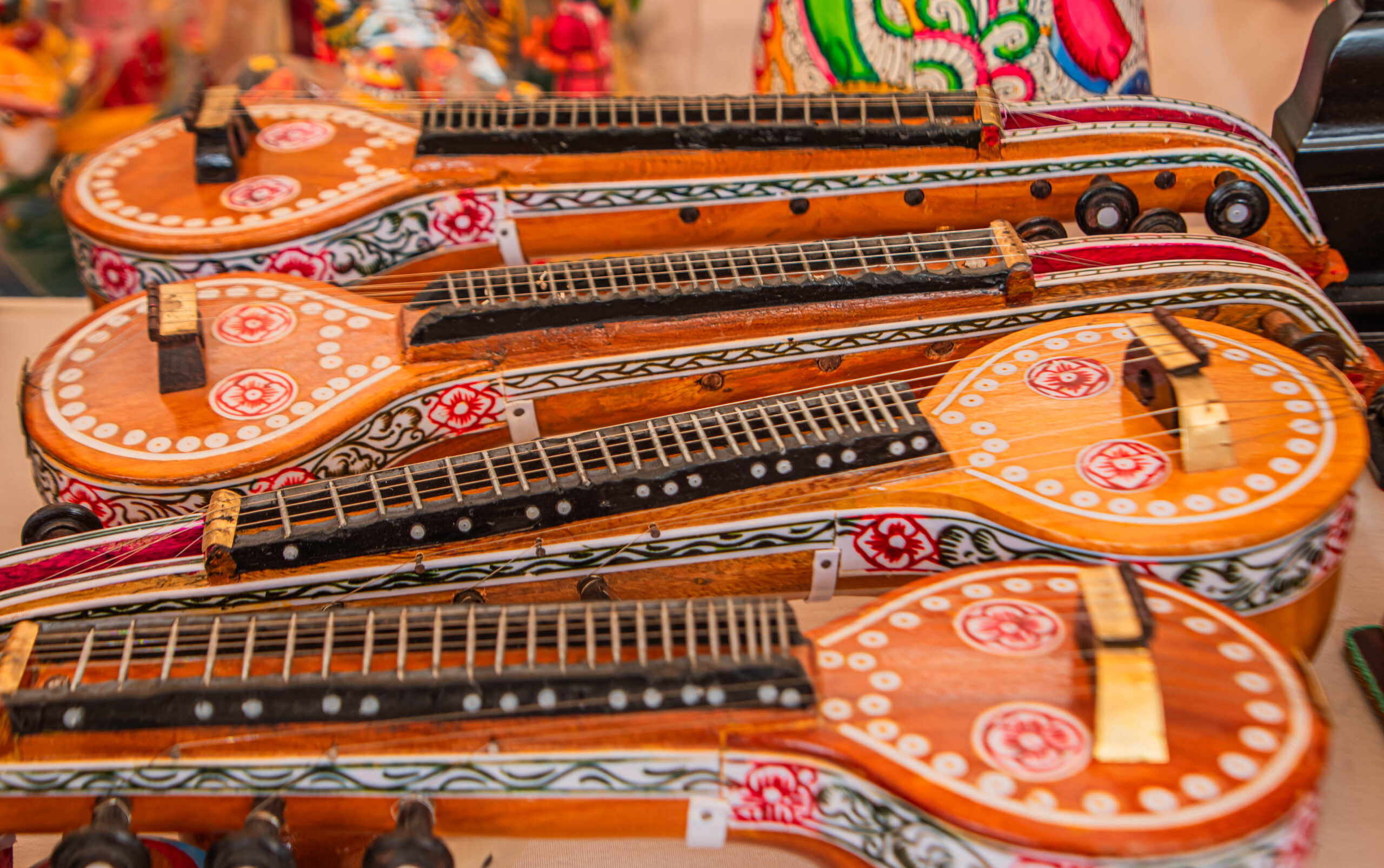 Wooden toy musical instruments resembling veenas arranged in a row.