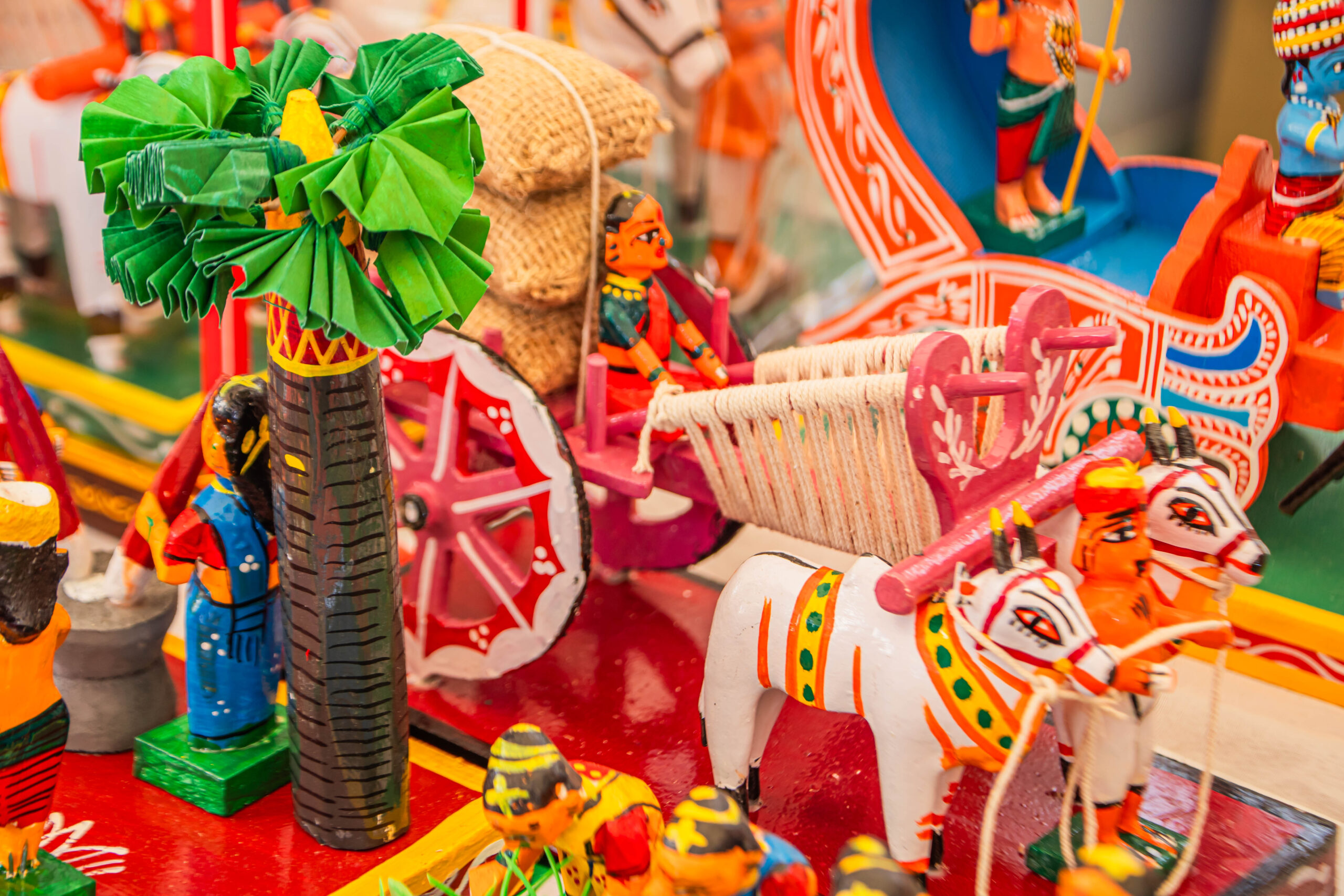 Miniature bullock cart with figures and village elements made from wood.