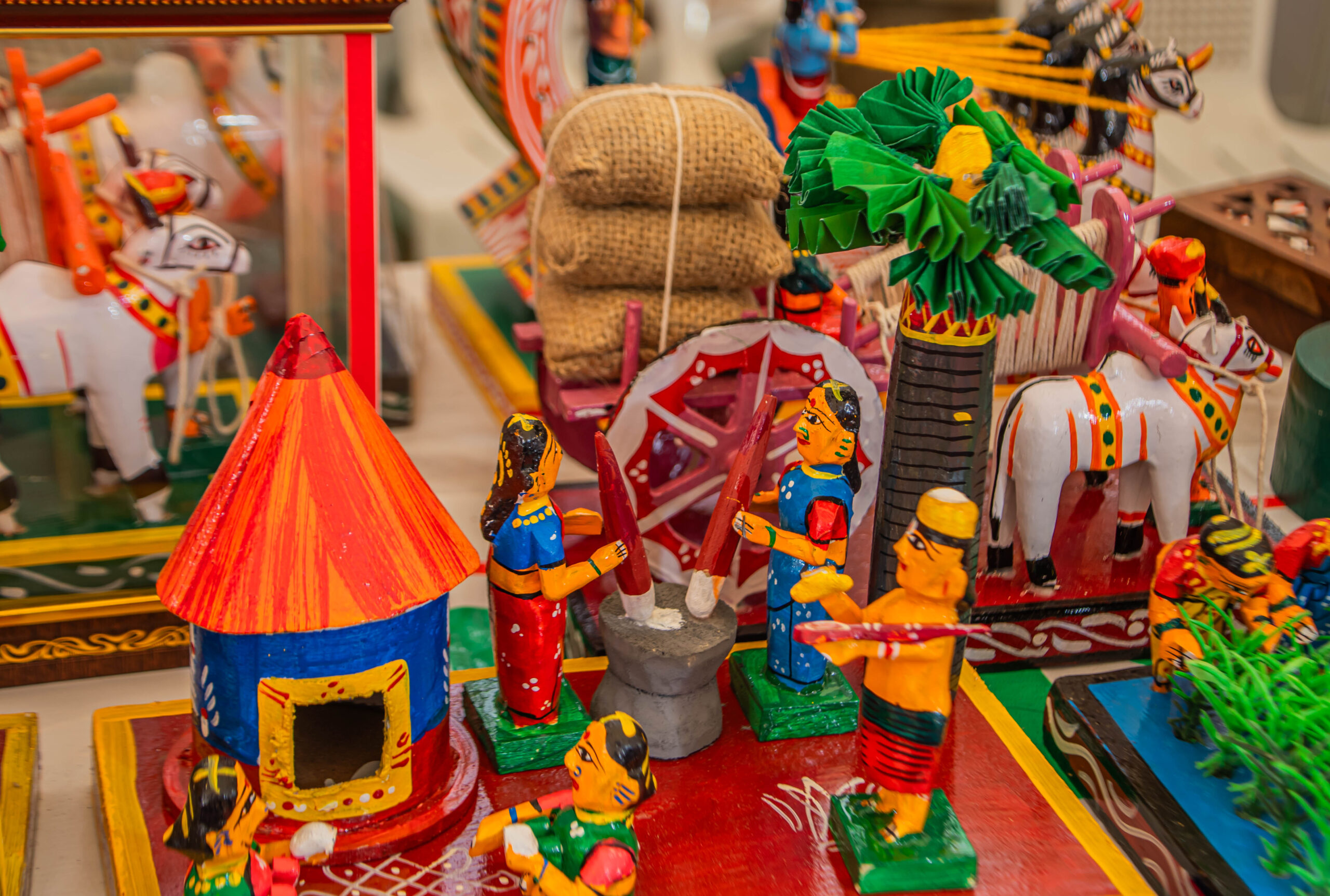 Miniature figures performing daily activities around a hut and tools.